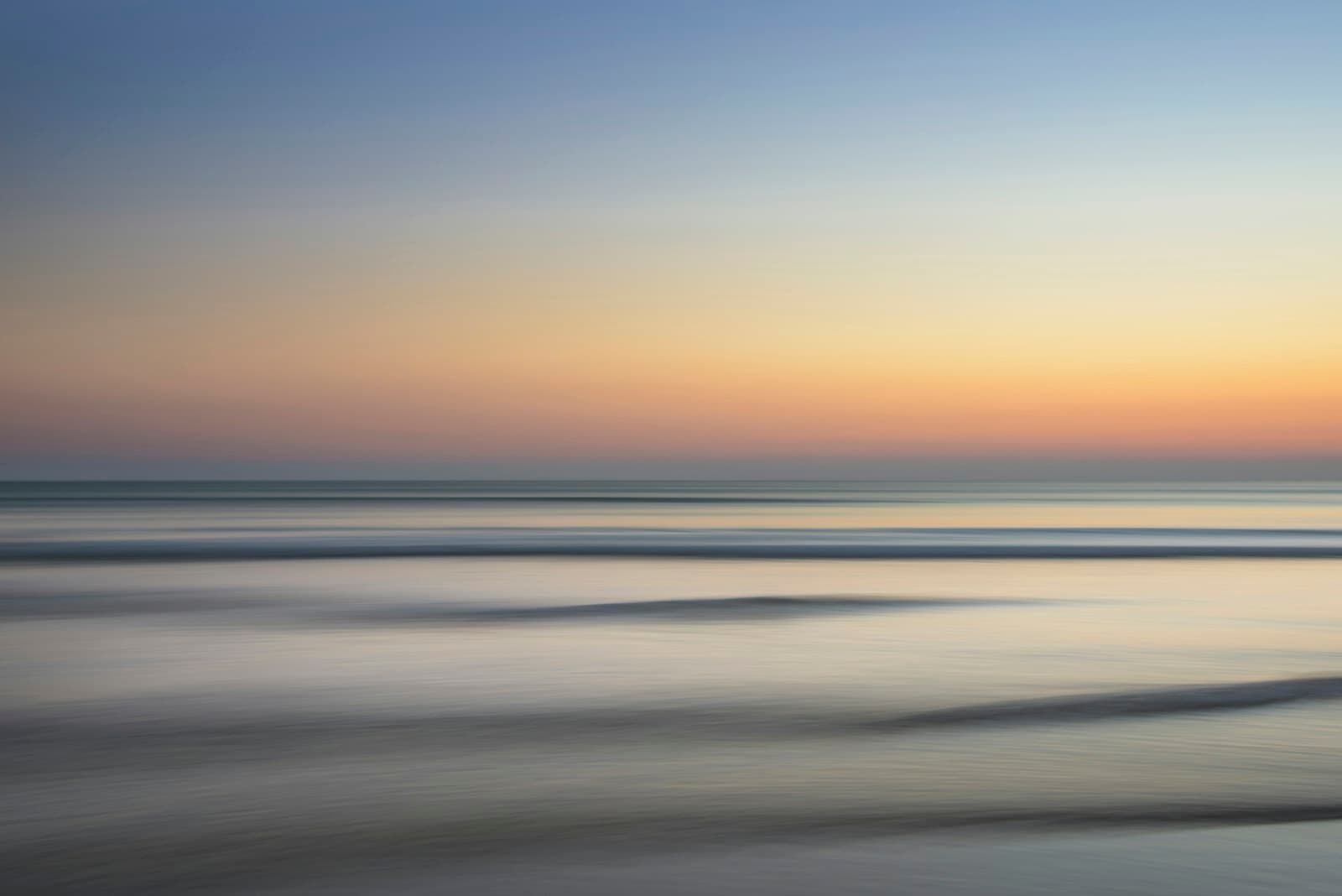 A calm golden sea under soft glowing clouds
