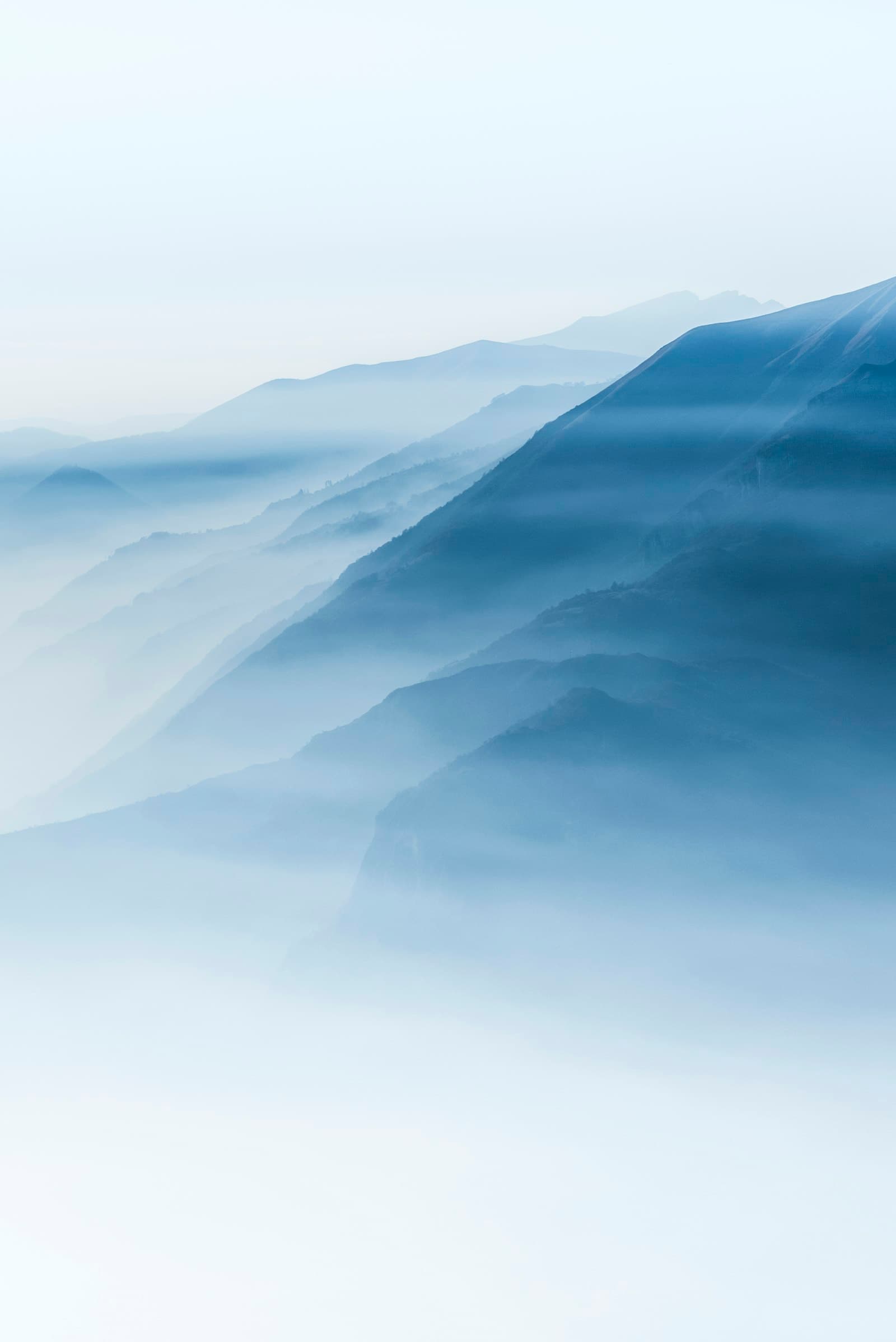 Soft blue layers of mist drifting between mountain ridges